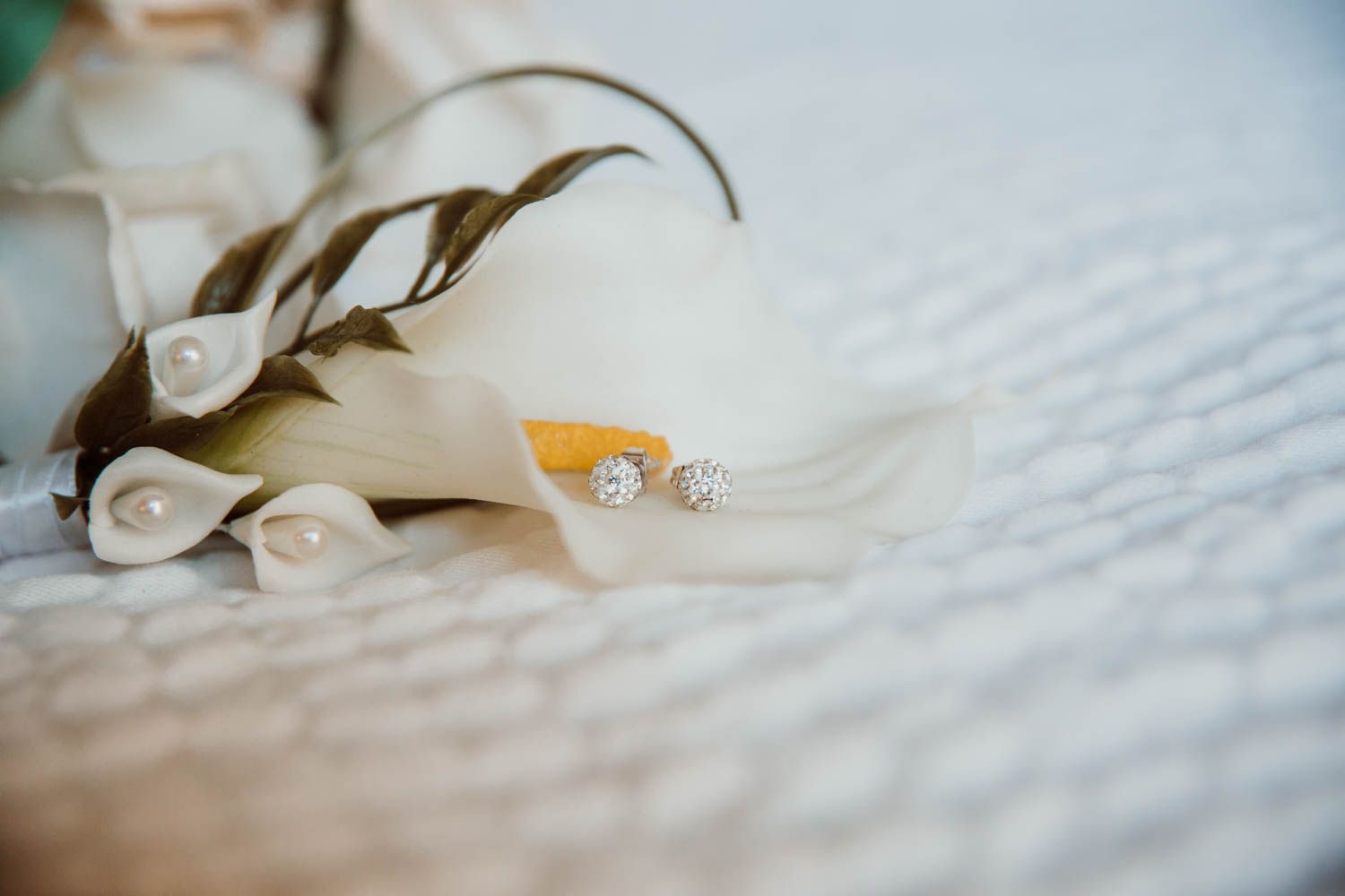 An elegant diamond engagement ring nestled in soft white calla lilies.