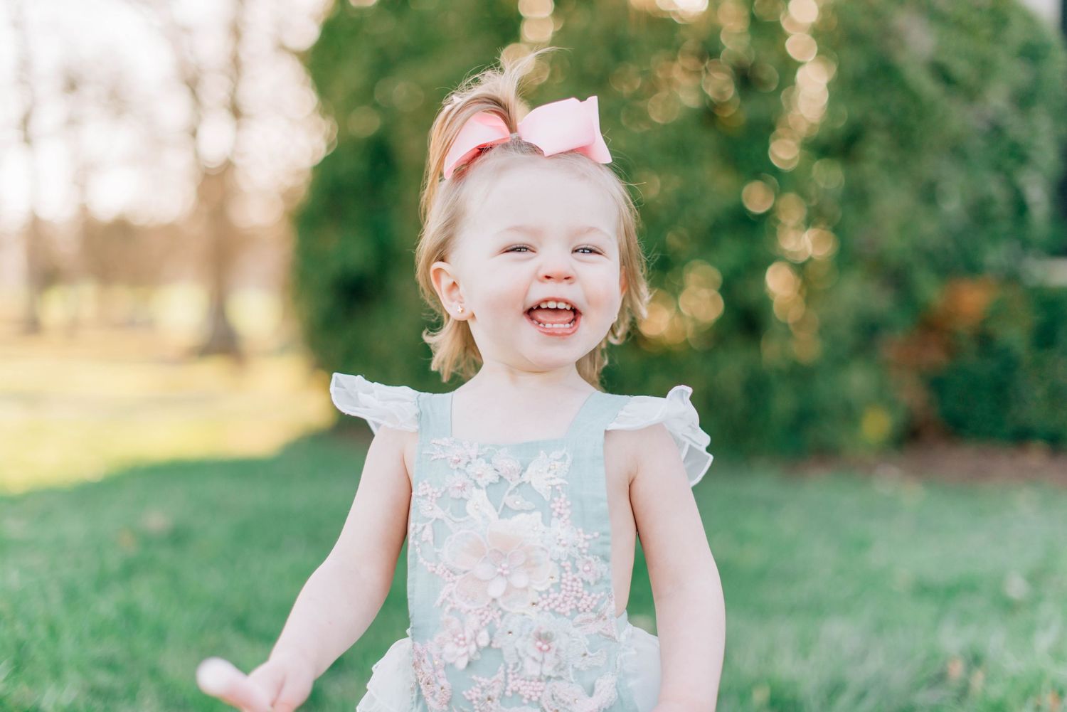A joyful toddler wearing a ruffled dress runs and plays in a sunny outdoor setting during golden hour.