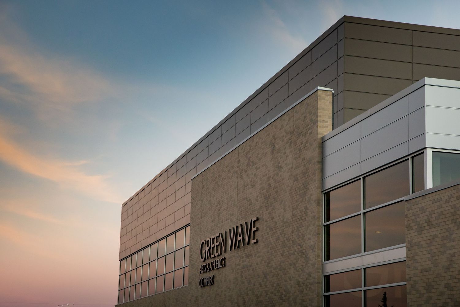 Modern commercial building exterior with glass windows and clean architectural lines at sunset.