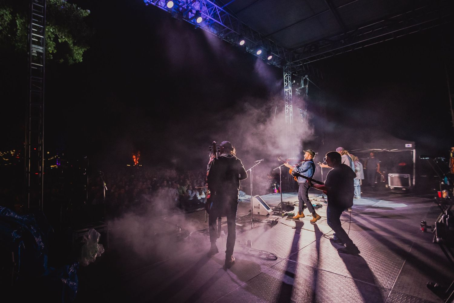 Silhouettes of concert attendees against atmospheric fog and dramatic lighting.