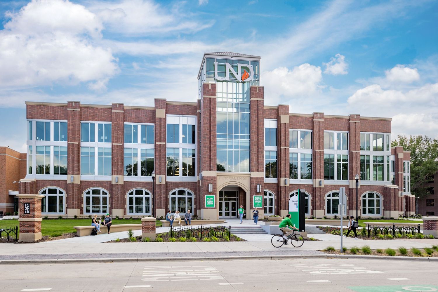 Modern brick university building exterior with glass windows under blue sky.