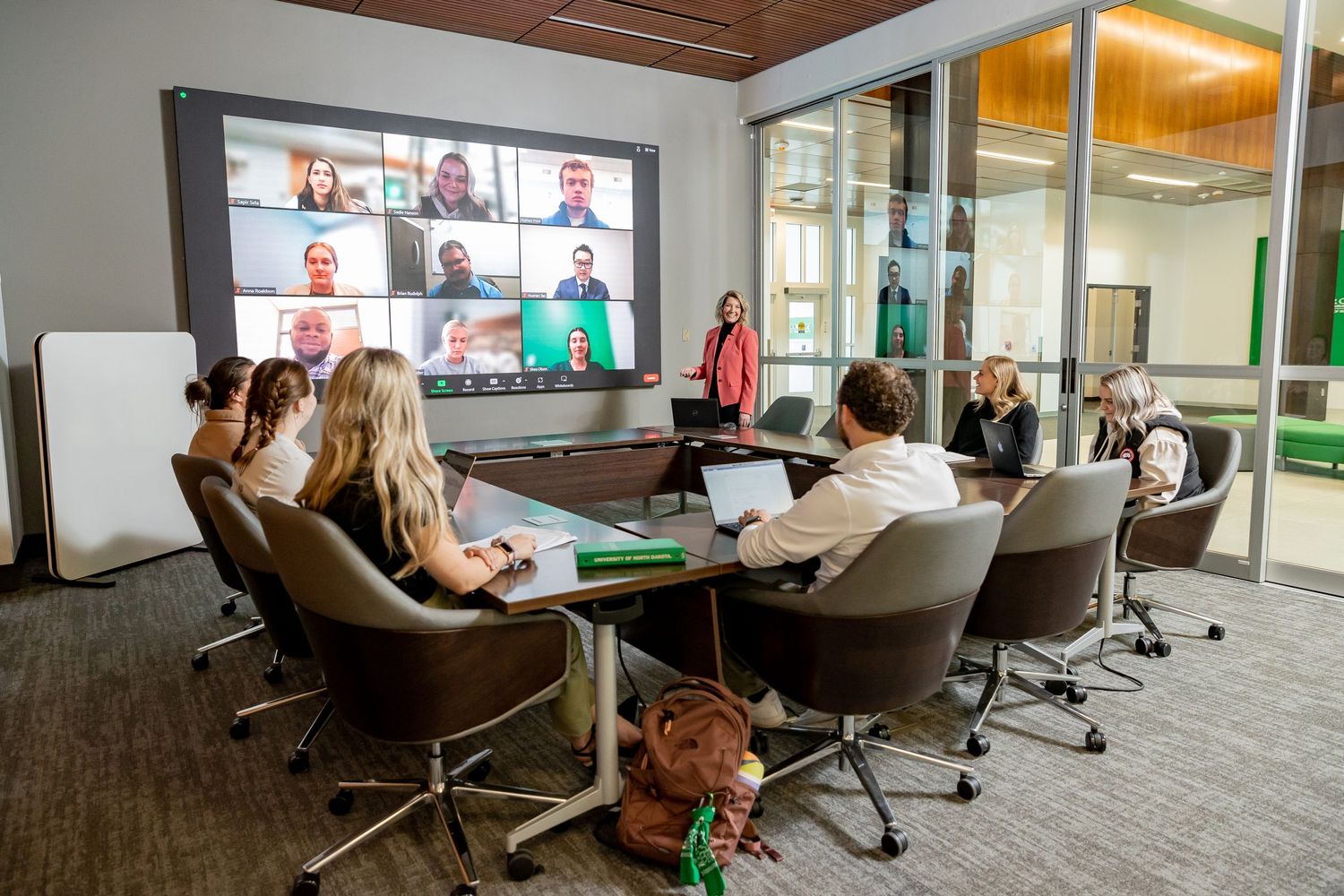 Corporate meeting room with video conference displays showing remote participants.