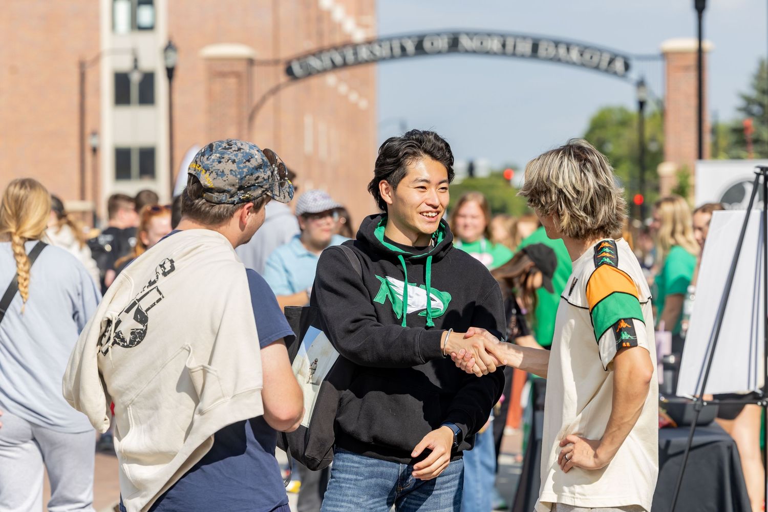 Students walking outside campus buildings on sunny day with university architecture visible.