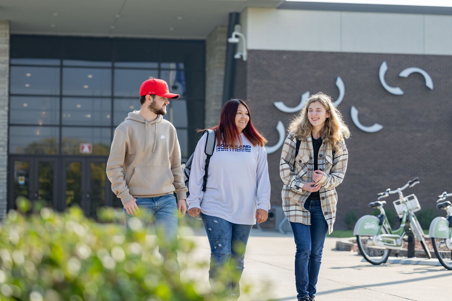 Students walking together outside a modern building with decorative wall art.