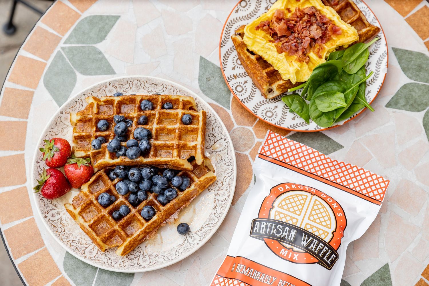 Fresh waffles topped with berries and syrup served on white plates with a restaurant menu.