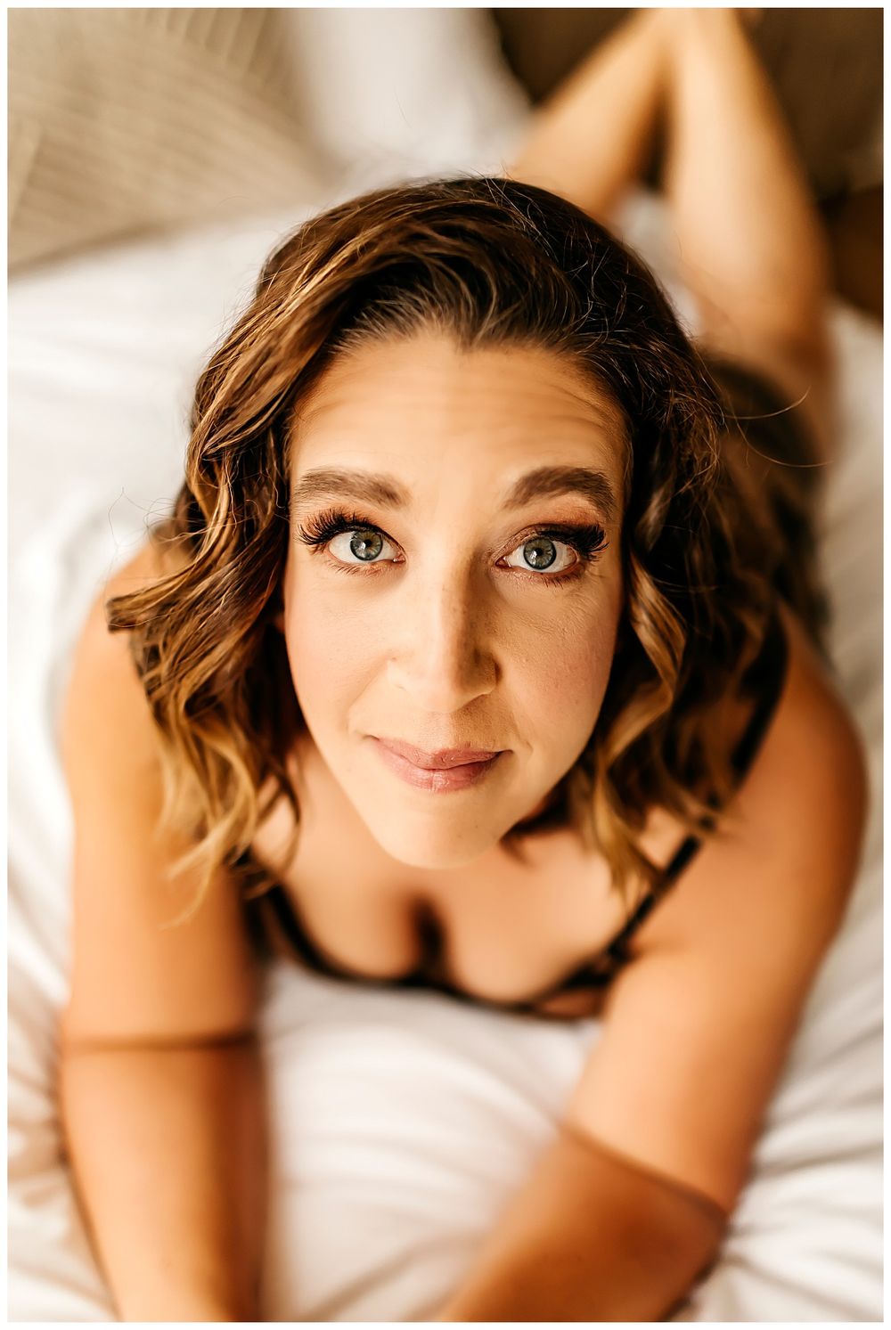 woman rests on elbows on bed during curvy boudoir session