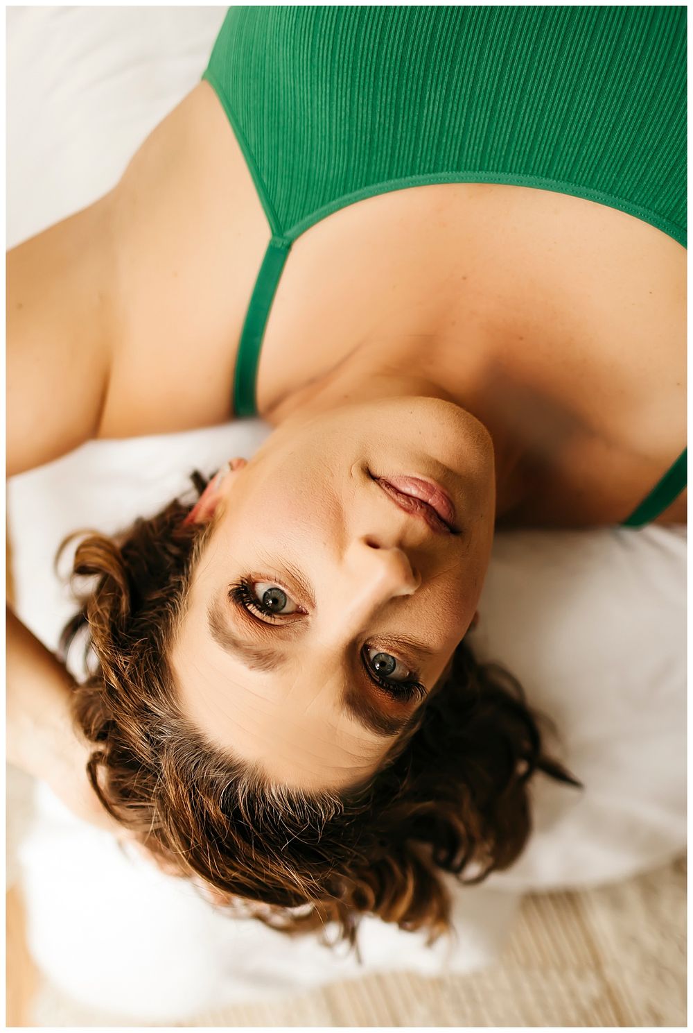 lady rests on bed with arm above head by Danielle Miranda Photography