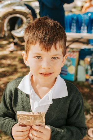 A child in a green sweater holding something at an outdoor event.