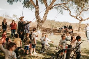 People gathered for an outdoor celebration under large eucalyptus trees.