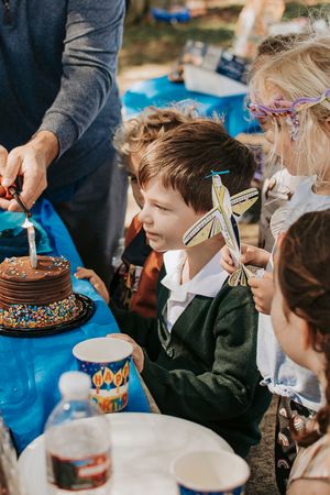 Birthday celebration with chocolate cake and party decorations outdoors.