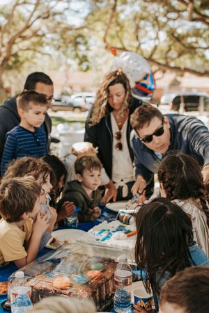 People gathered around a picnic table at an outdoor party.