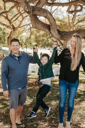 Playful candid shots of a family enjoying quality time outdoors under a shady tree.