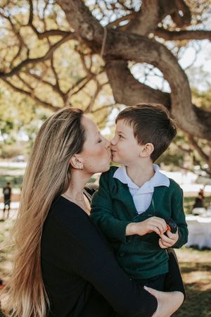 Tender family moment shared under the branches of a sprawling tree.