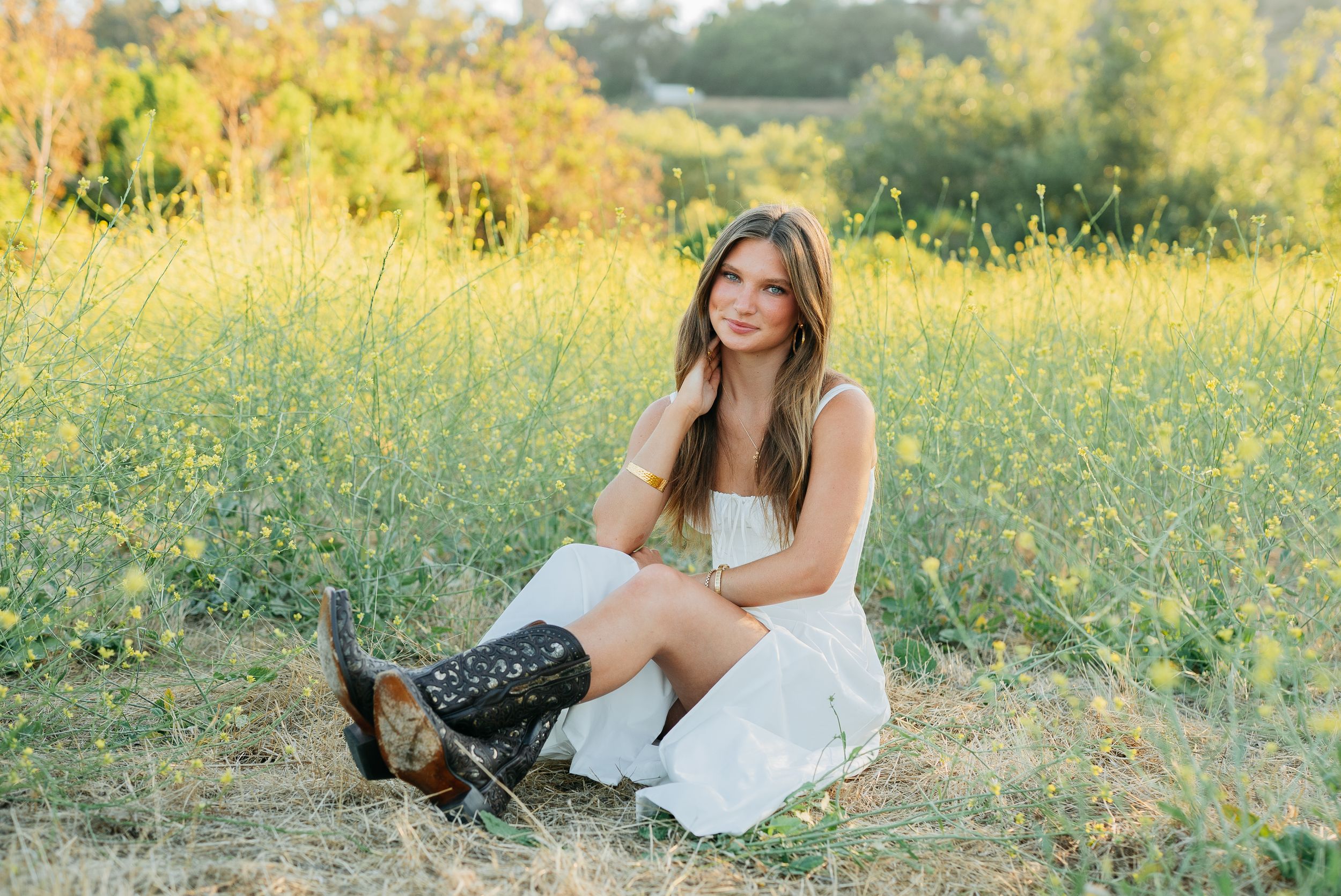 Sunlit outdoor portraits in a field of yellow wildflowers wearing a casual white dress.