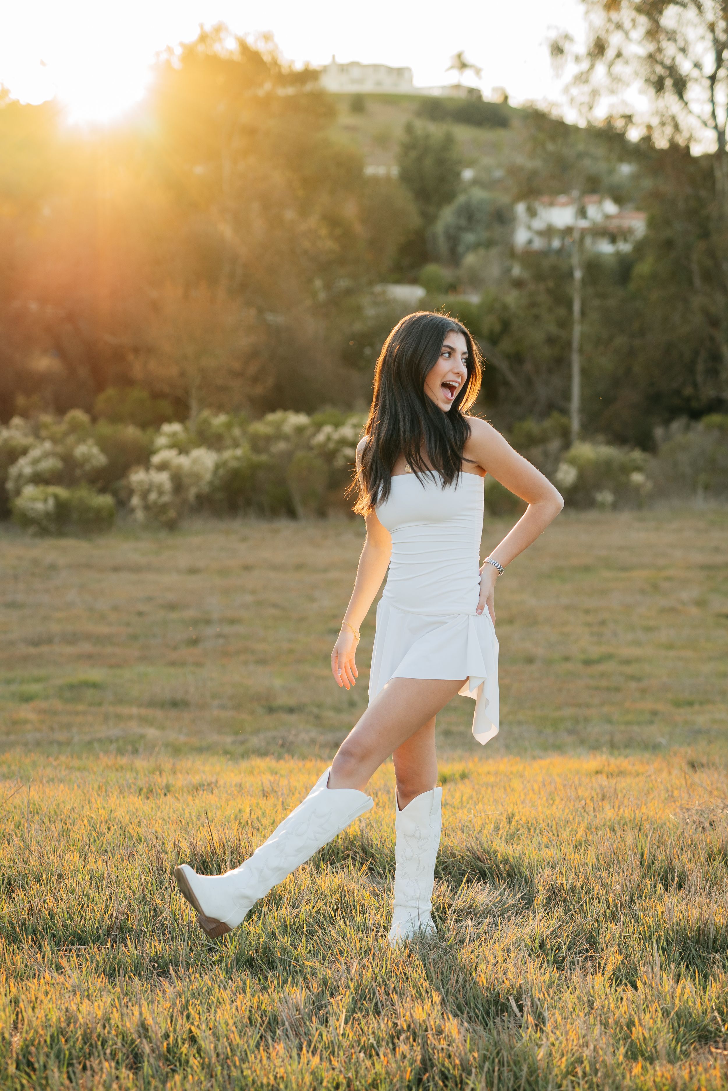 Playful poses in a grassy field at sunset wearing white casual attire and sneakers.