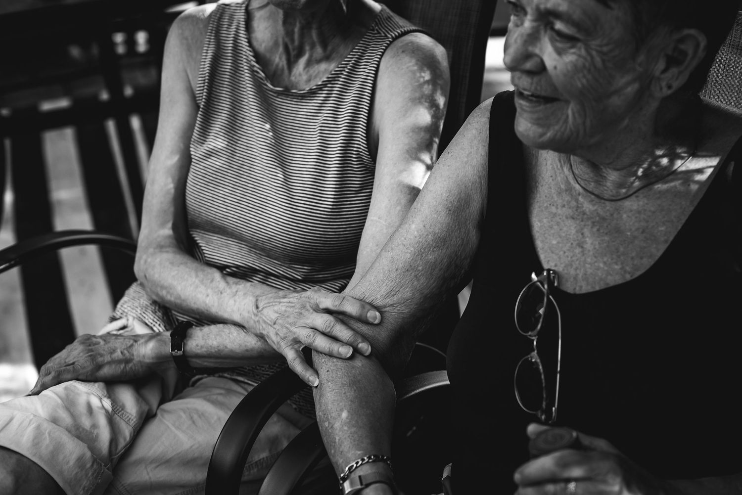 BW image of the arms of two women, one is touching the other's elbow.