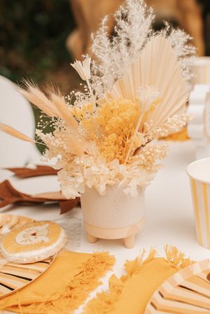 Dried floral arrangement with pampas grass and preserved flowers in beige and yellow tones.