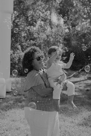Black and white photo of people playing with bubbles in a garden setting.