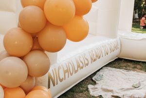 Orange balloon arch decoration with text displayed on a white surface.