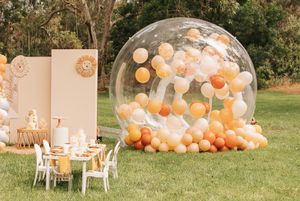 Outdoor party setup with balloon arch and decorated tables in garden setting.