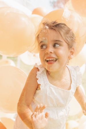 Peach-toned party setting with white balloons and soft lighting.