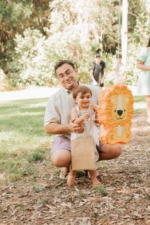 A festive outdoor gathering with an orange lion piñata and fallen leaves on the ground.