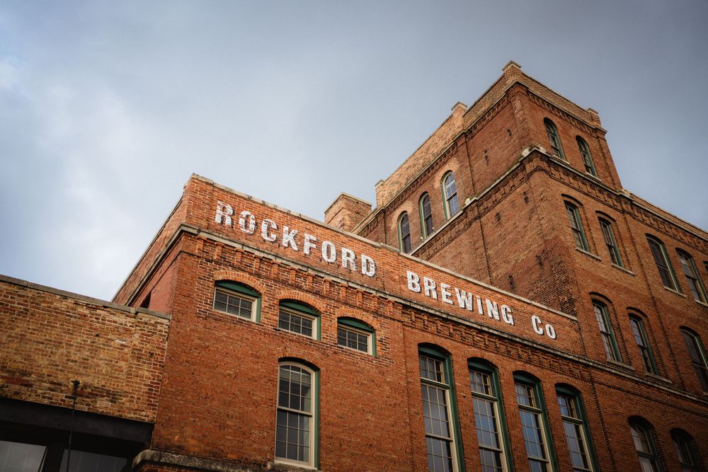 Historic Rockford Brewing Company building exterior with red brick facade against cloudy sky.