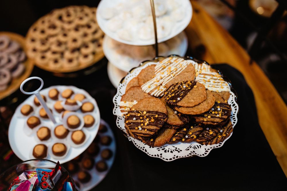 Elegant display of chocolate desserts and cookies on silver platters at wedding reception.