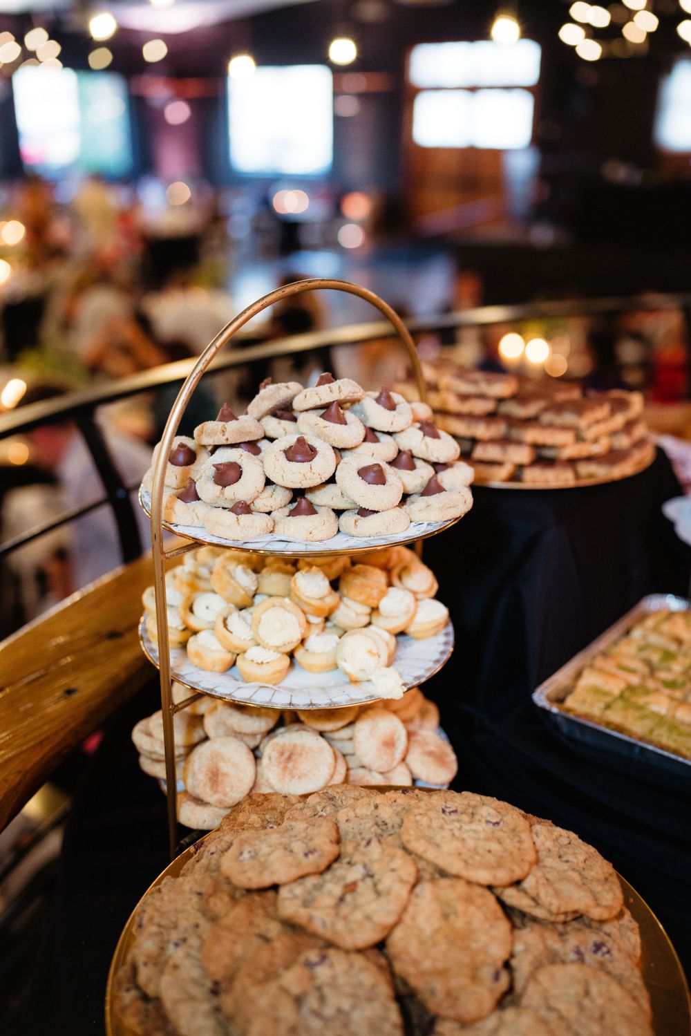 Tiered dessert stand filled with cookies and treats at wedding reception.