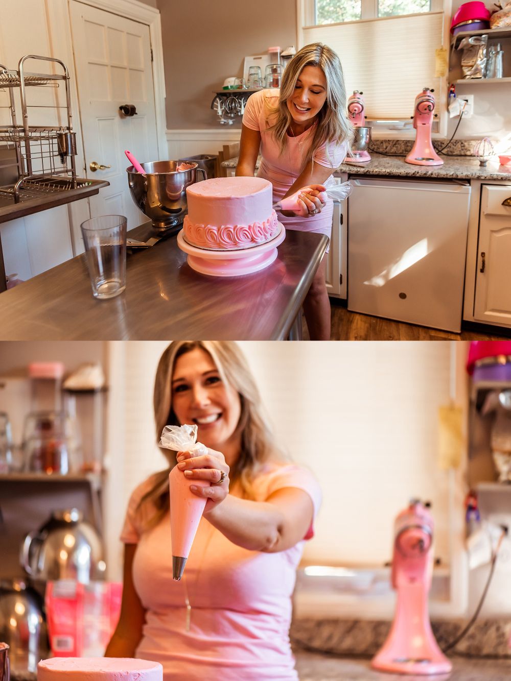 Baker decorating a pink layer cake in a bright kitchen with baking tools and equipment.