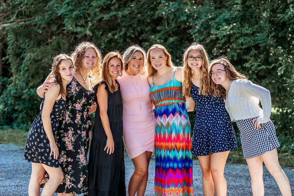 Group photo of friends in summer dresses posing together outdoors.