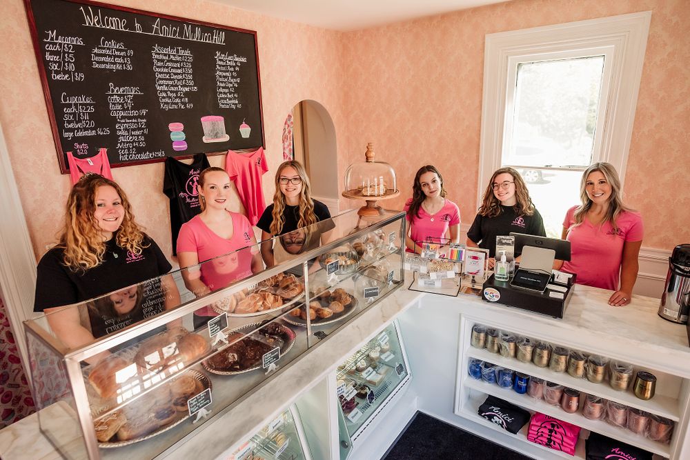 Bakery staff working behind a glass display counter with a chalkboard menu on the wall.