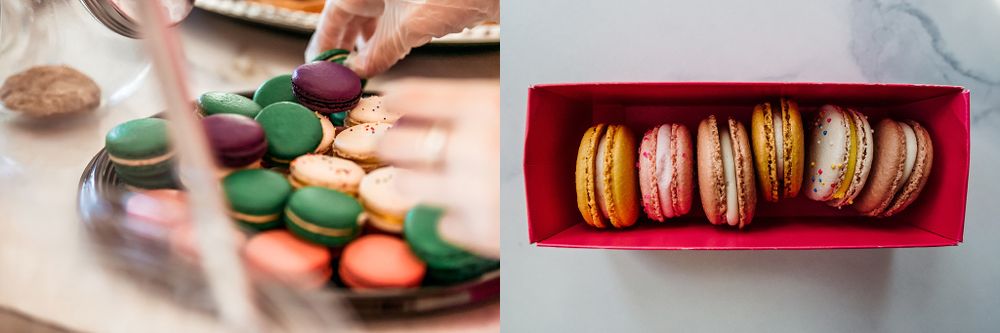 Hands arranging vibrant green and orange macarons next to a red box of assorted French macarons.