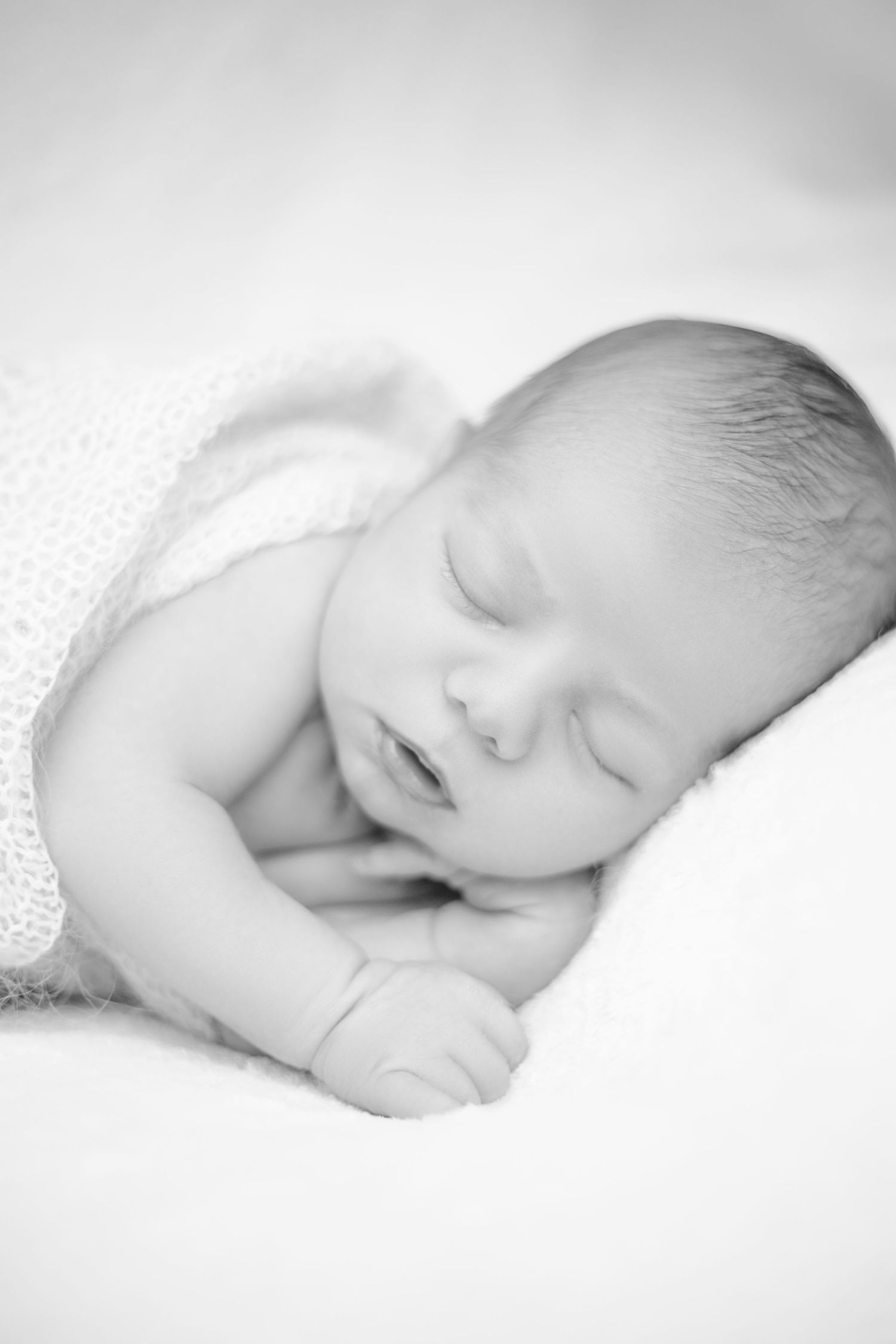 Series of black and white newborn baby photos showing peaceful sleeping poses.