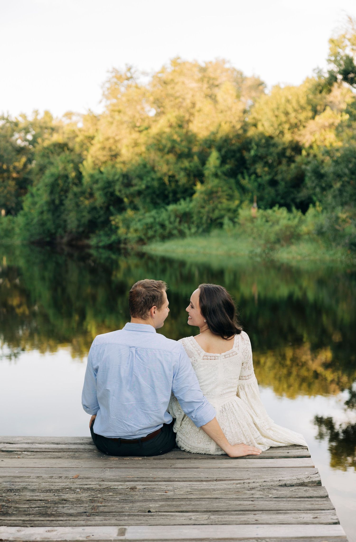 Couple sitting on a dock during their engagement session in Sarasota FL, taken by Sarasota Wedding Photographer.