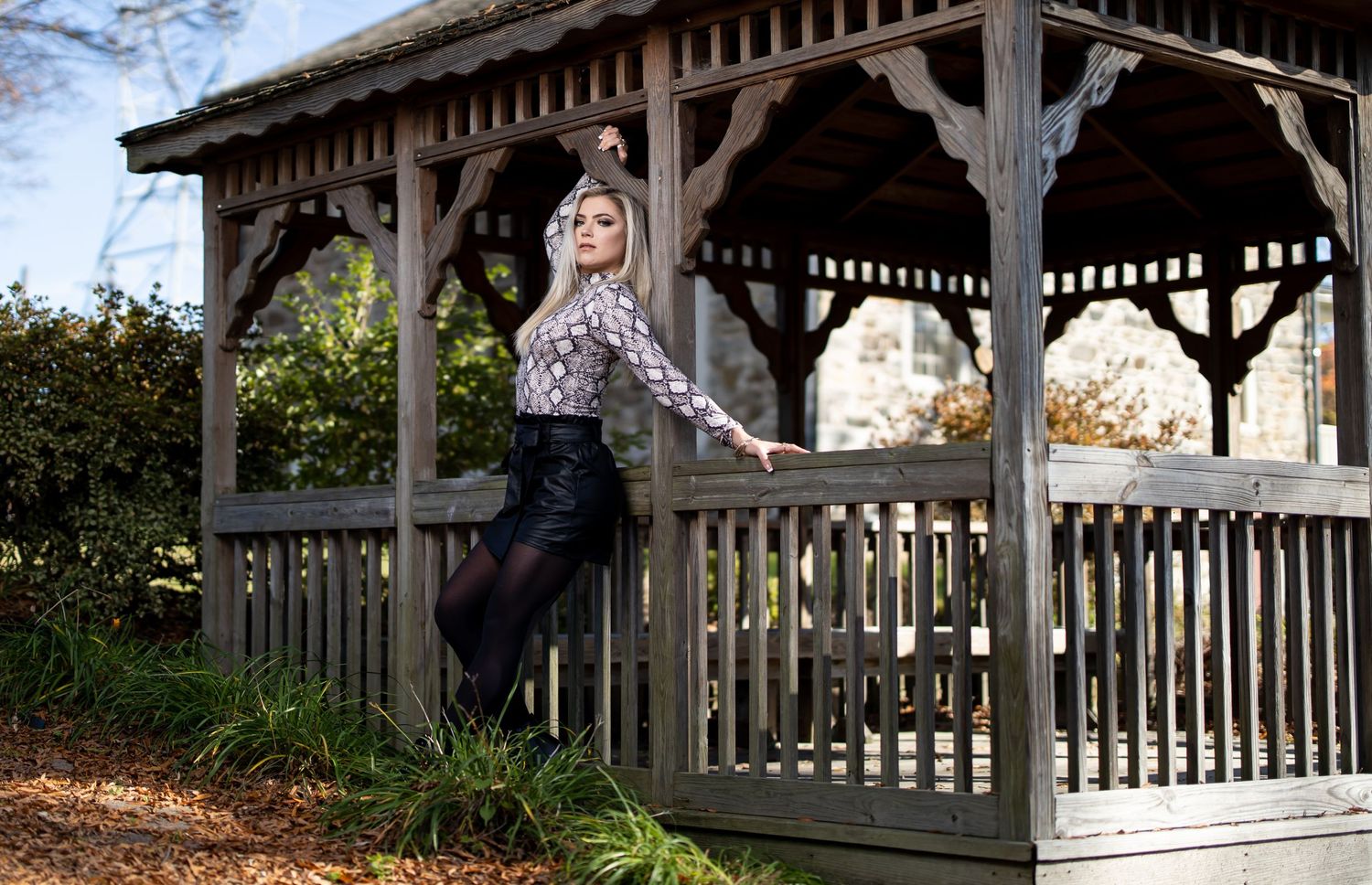 Fashion portrait in rustic wooden gazebo with stylish outdoor setting.