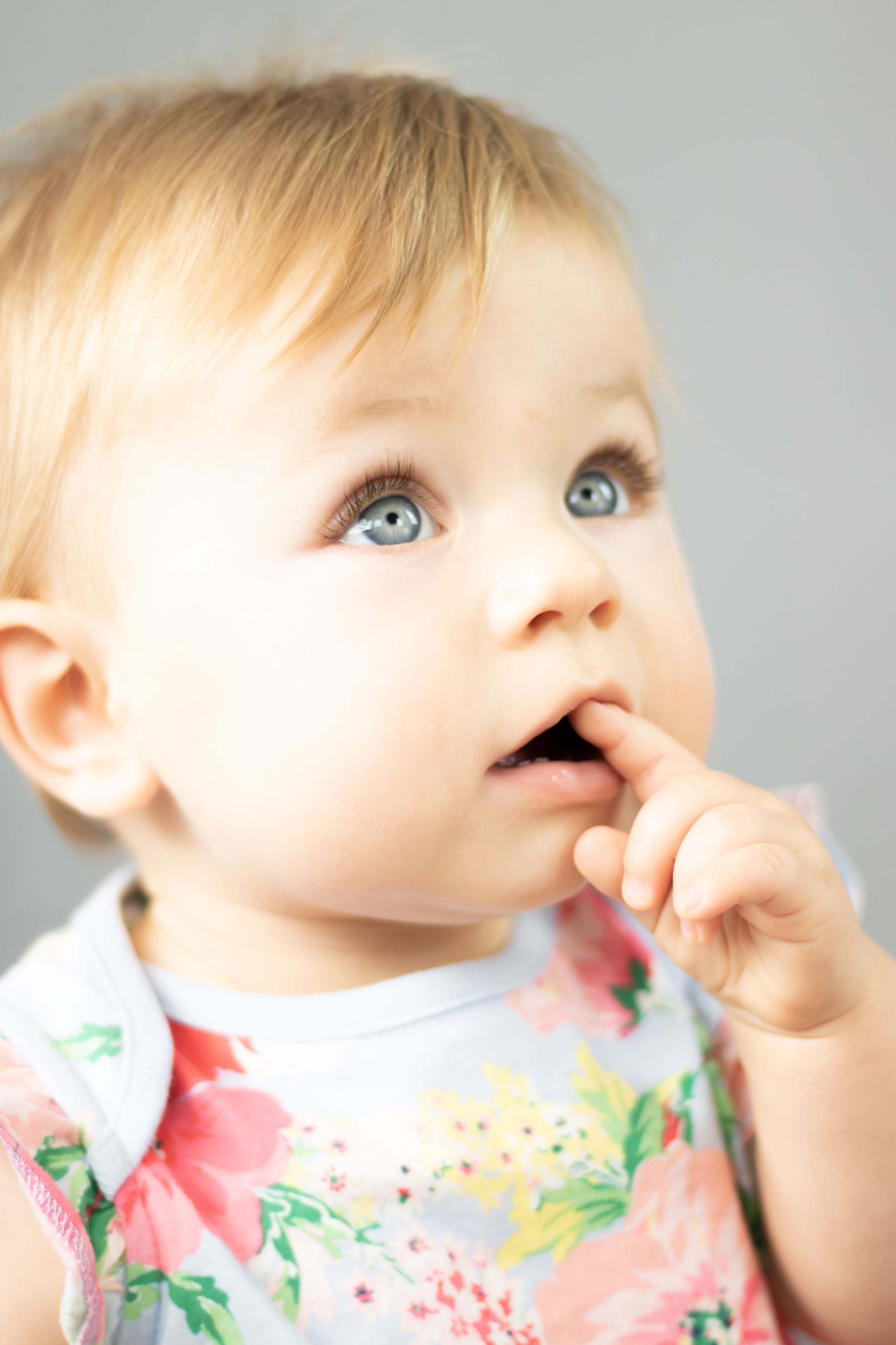 3 month girl looking up with an inquisitive look on her face shining along hair and blue eyes