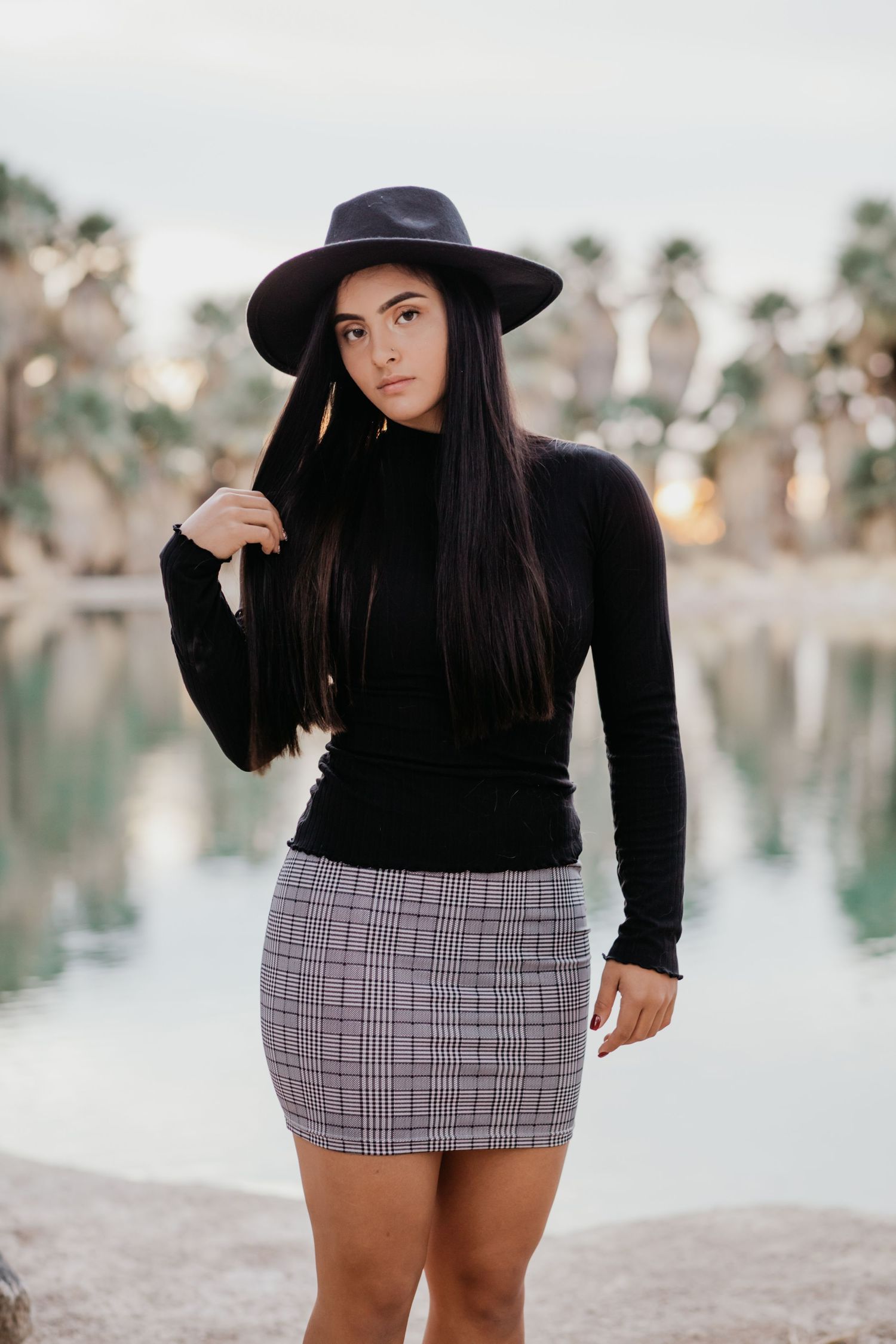 Tucson portrait session of a young woman in a black hat and sweater posing outdoors with soft natural light.