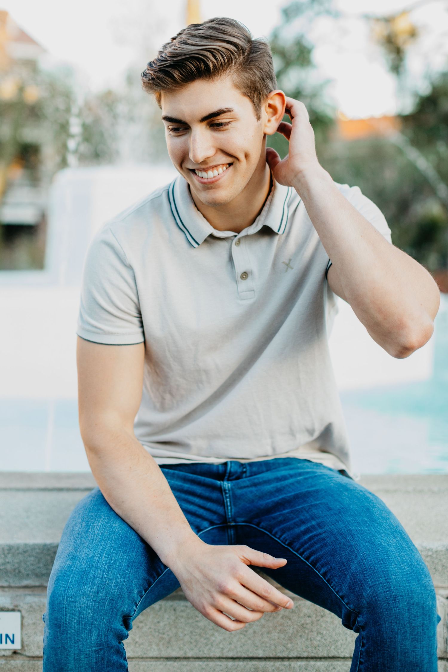 Tucson senior portrait of a young man sitting casually with a relaxed, confident smile in soft outdoor light.