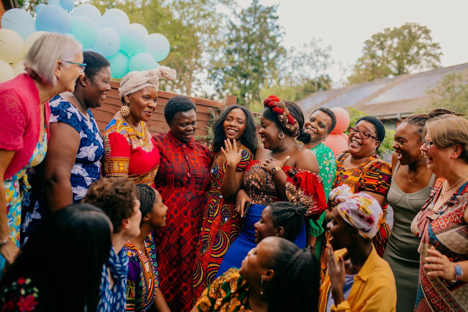 A large group of women smile and laugh at a family celebration in the garden