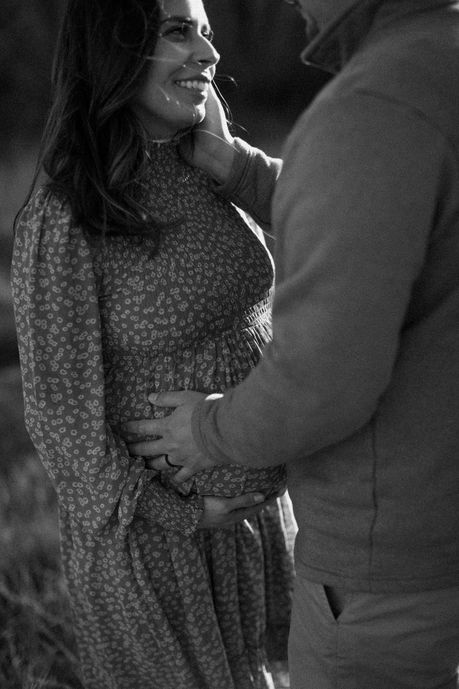 An intimate black and white portrait of a couple sharing a tender moment outdoors.