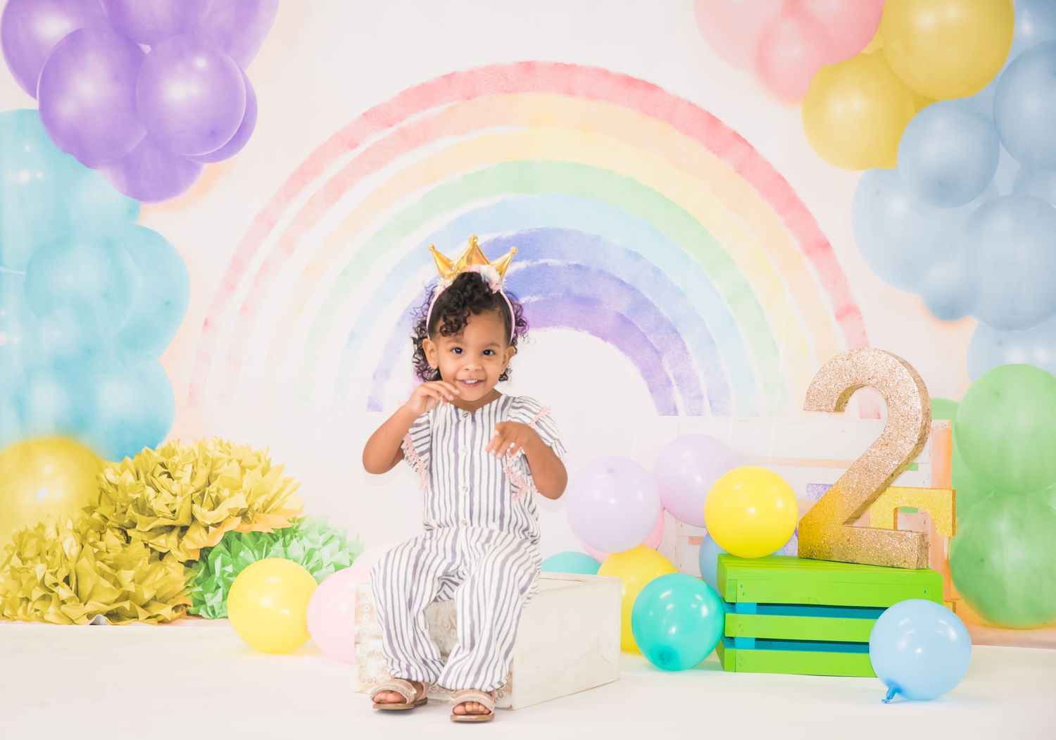 Colorful rainbow themed birthday setup with balloons and pastel decorations.
