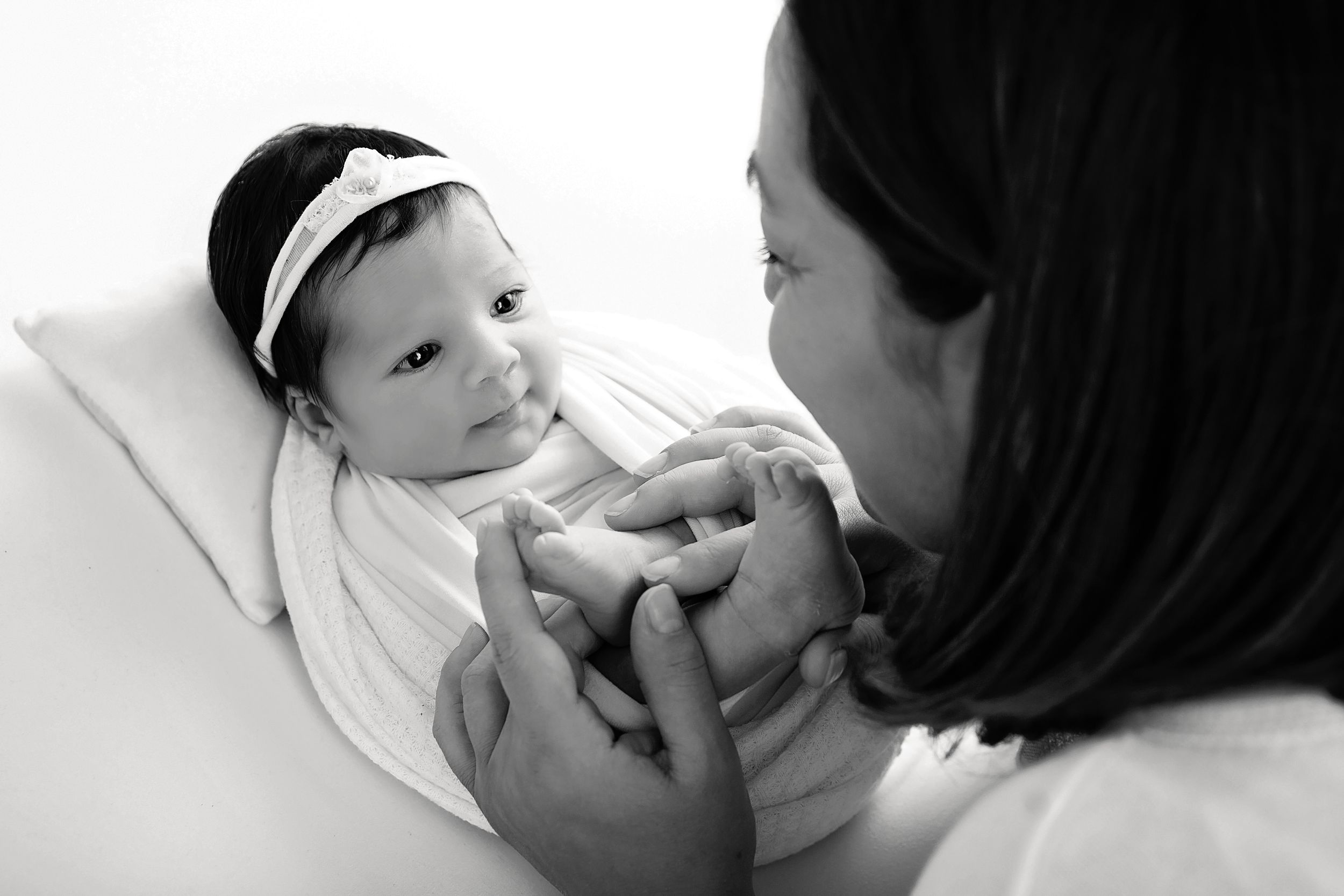Black and white close-up portrait series showing tender newborn details against white background.