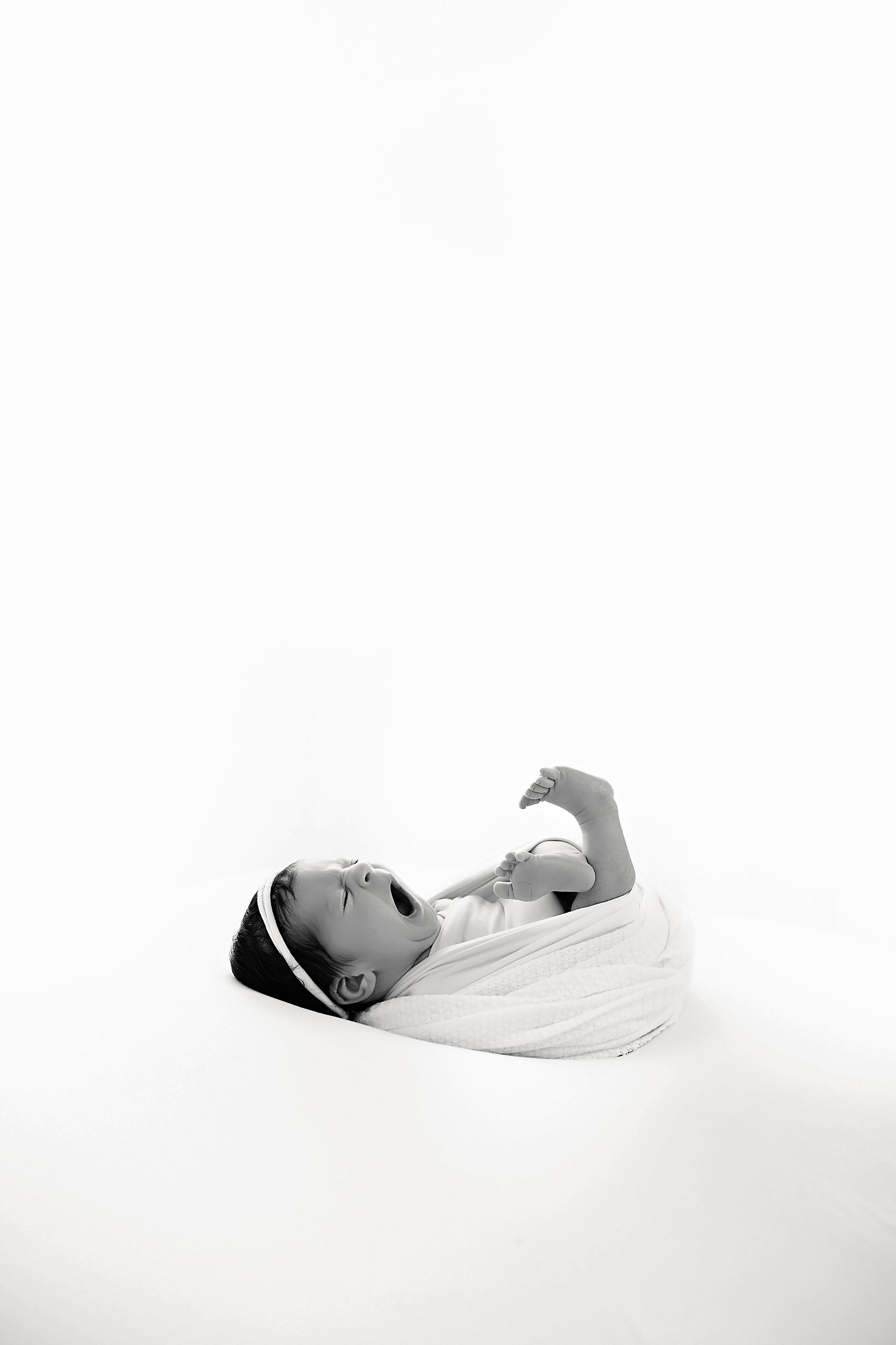Minimalist black and white series showing peaceful sleeping newborn in white setting.