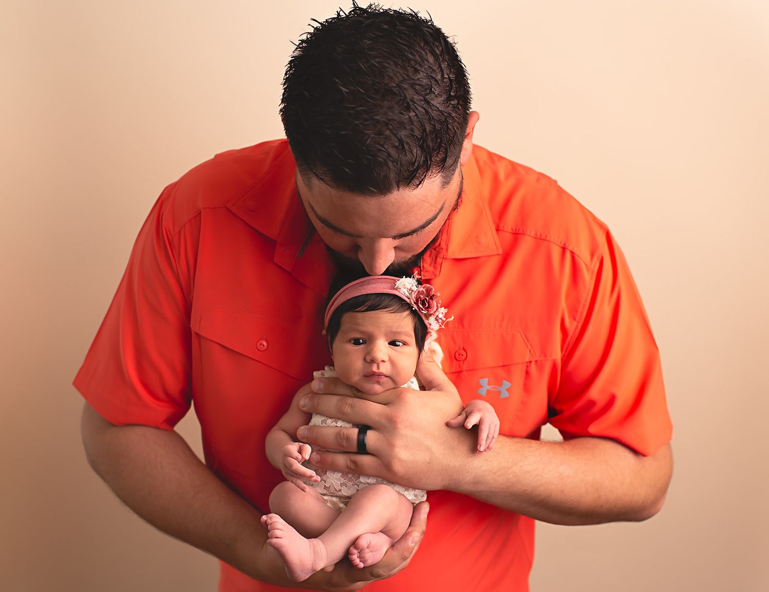 Dad holding newborn baby daughter and kissing her headin Alvin, Tx photographer studio