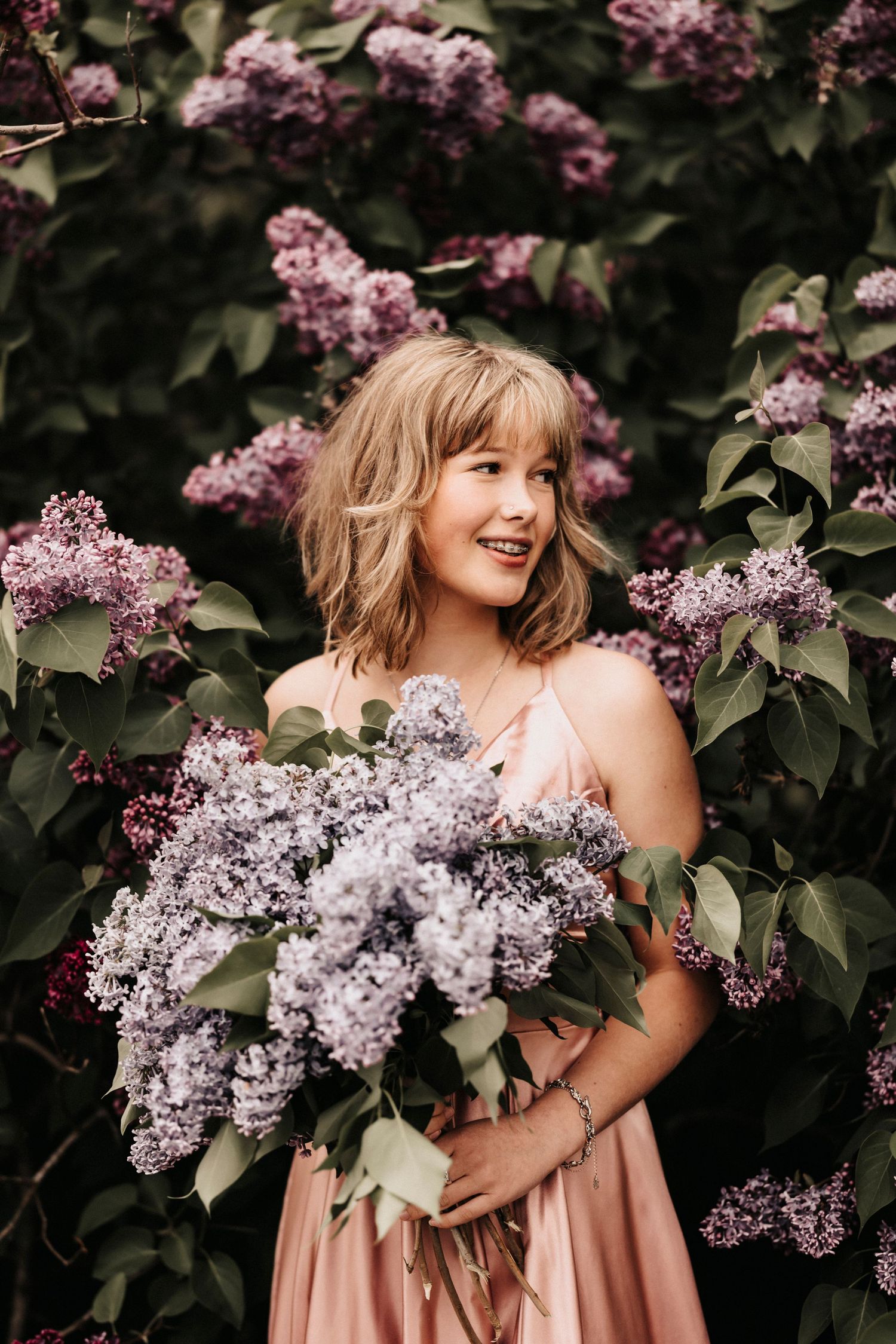 Joyful moment captured among blooming lilac bushes holding fresh-cut flowers.