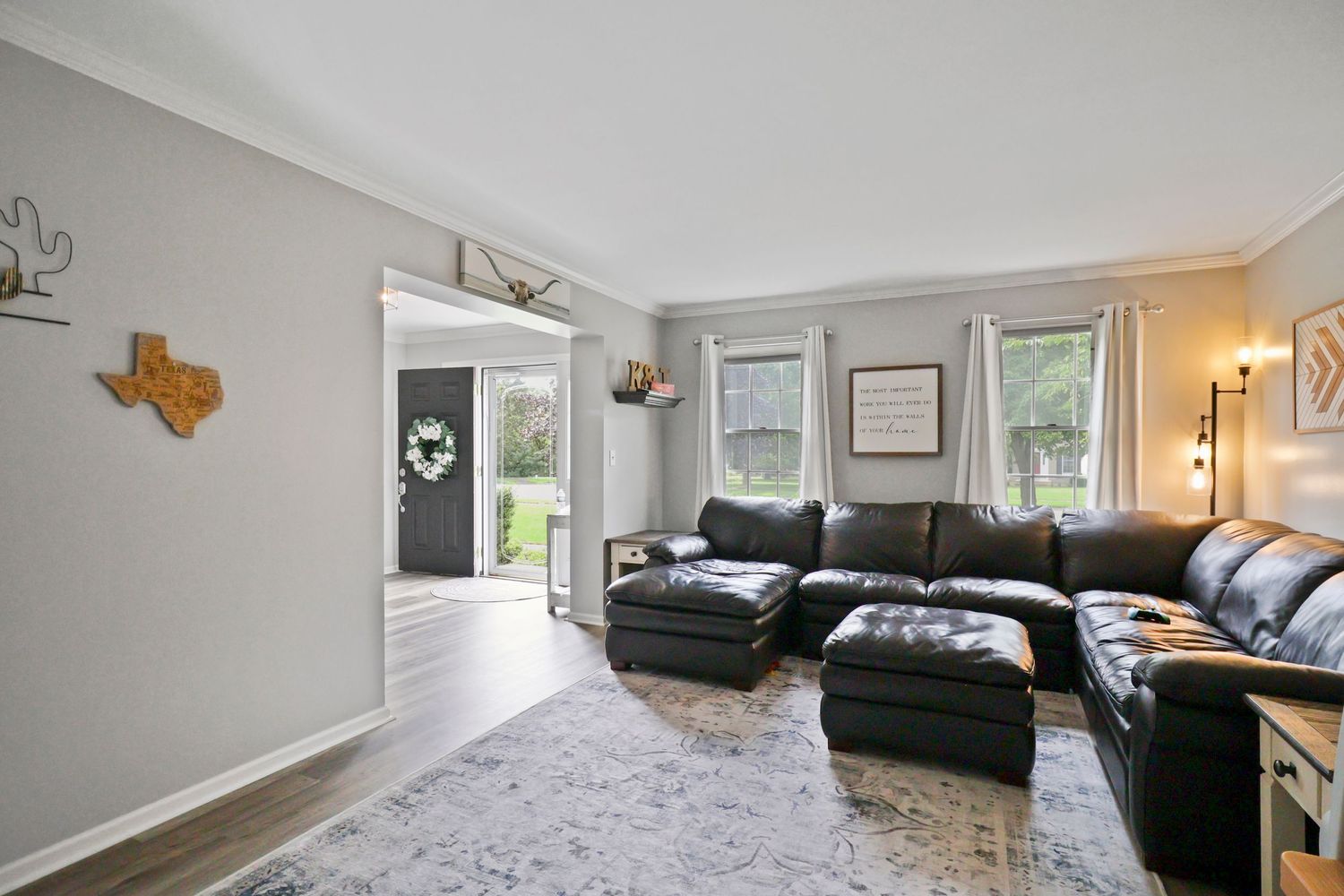 Spacious living area with modern furnishings, gray walls, and natural lighting from windows.