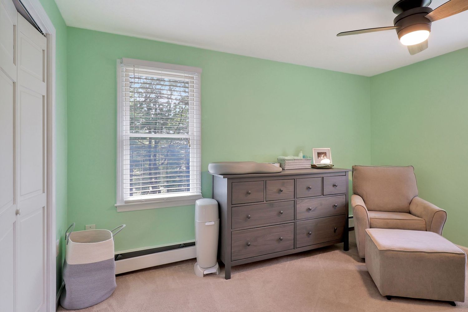 Modern bedroom with mint green walls, hardwood floors, and natural lighting from large windows.