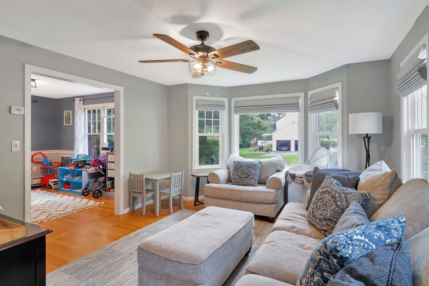 Living room with ceiling fan, grey walls, and comfortable seating arrangement.