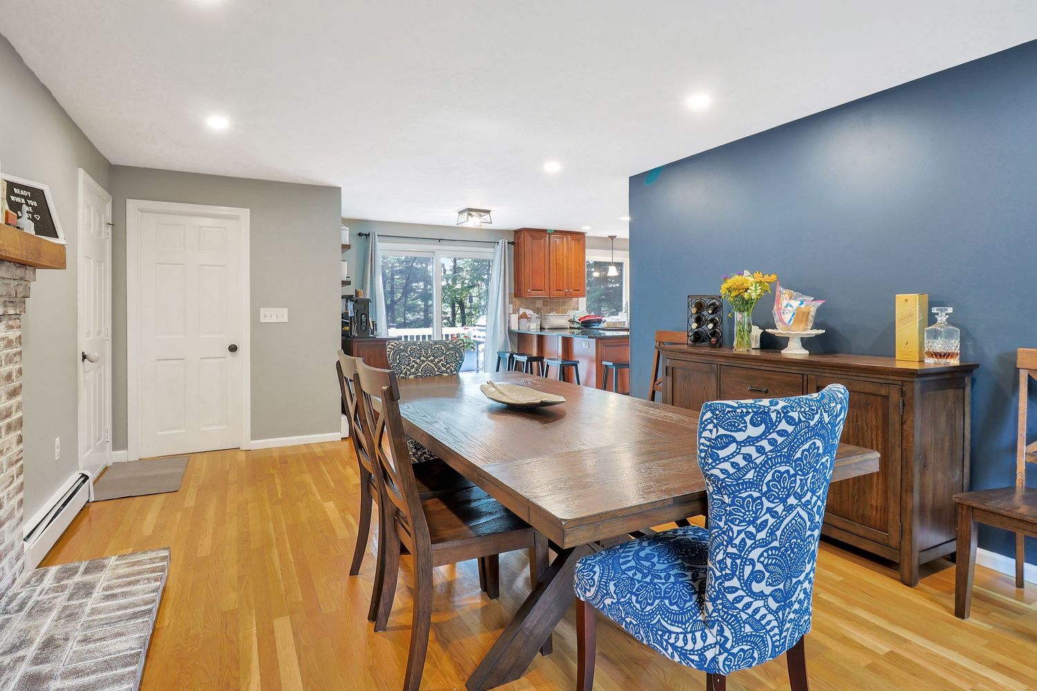 Dining area featuring blue accent chairs, hardwood floors, and modern lighting fixtures.